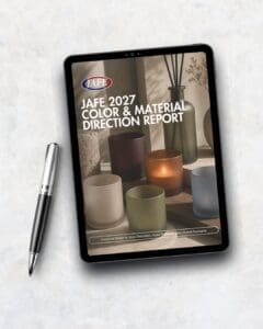 iPad displaying JAFE 2027 Color & Material Direction Report with decorated candle jars and glass containers on screen, silver pen beside it on white marble background