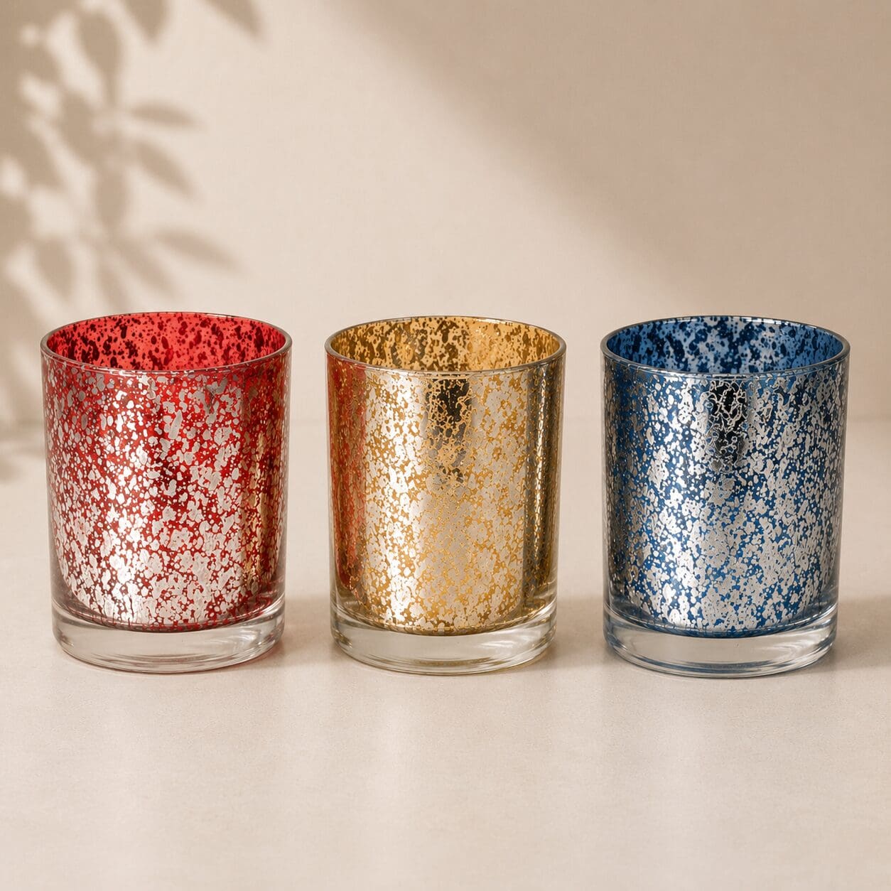 Three decorative glass jars with speckled finishes in red, gold, and blue, displaying custom glass screen printing and candle jar decorating