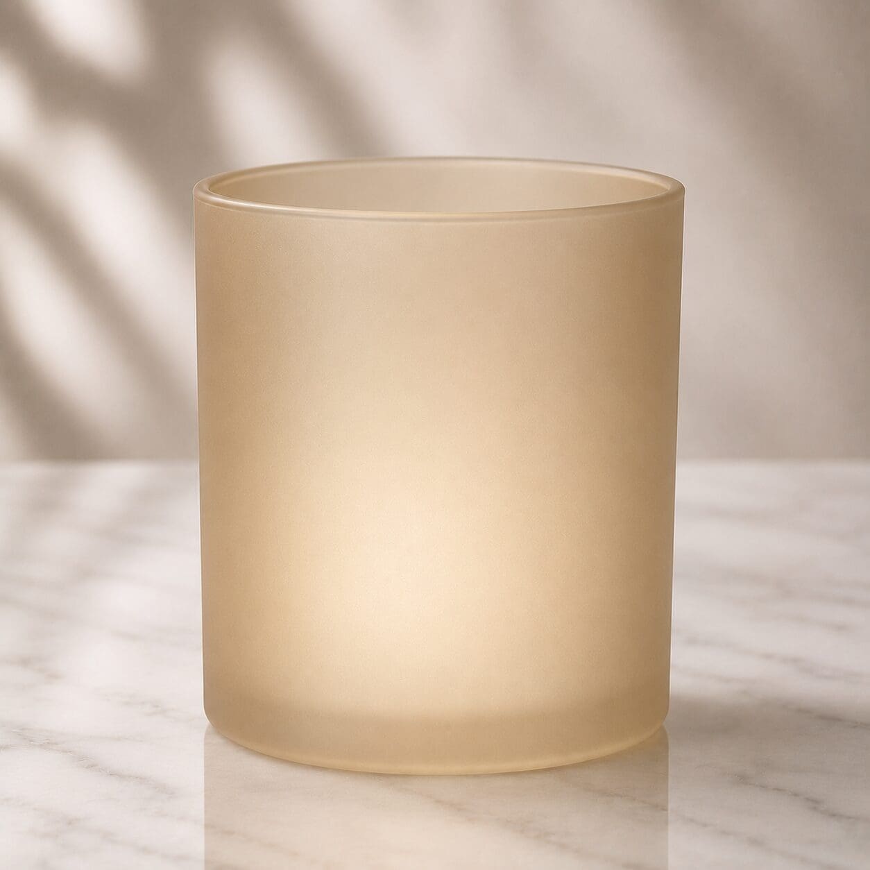 Frosted glass cylinder jar on marble surface with soft natural lighting and shadow backdrop