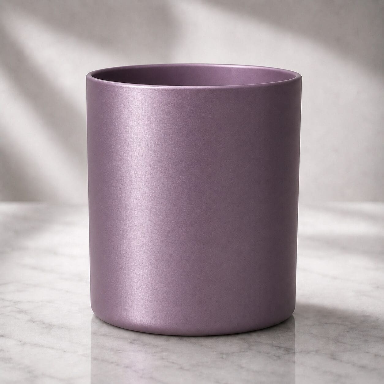 Mauve cylindrical ceramic vessel with satin finish on marble surface with soft window lighting