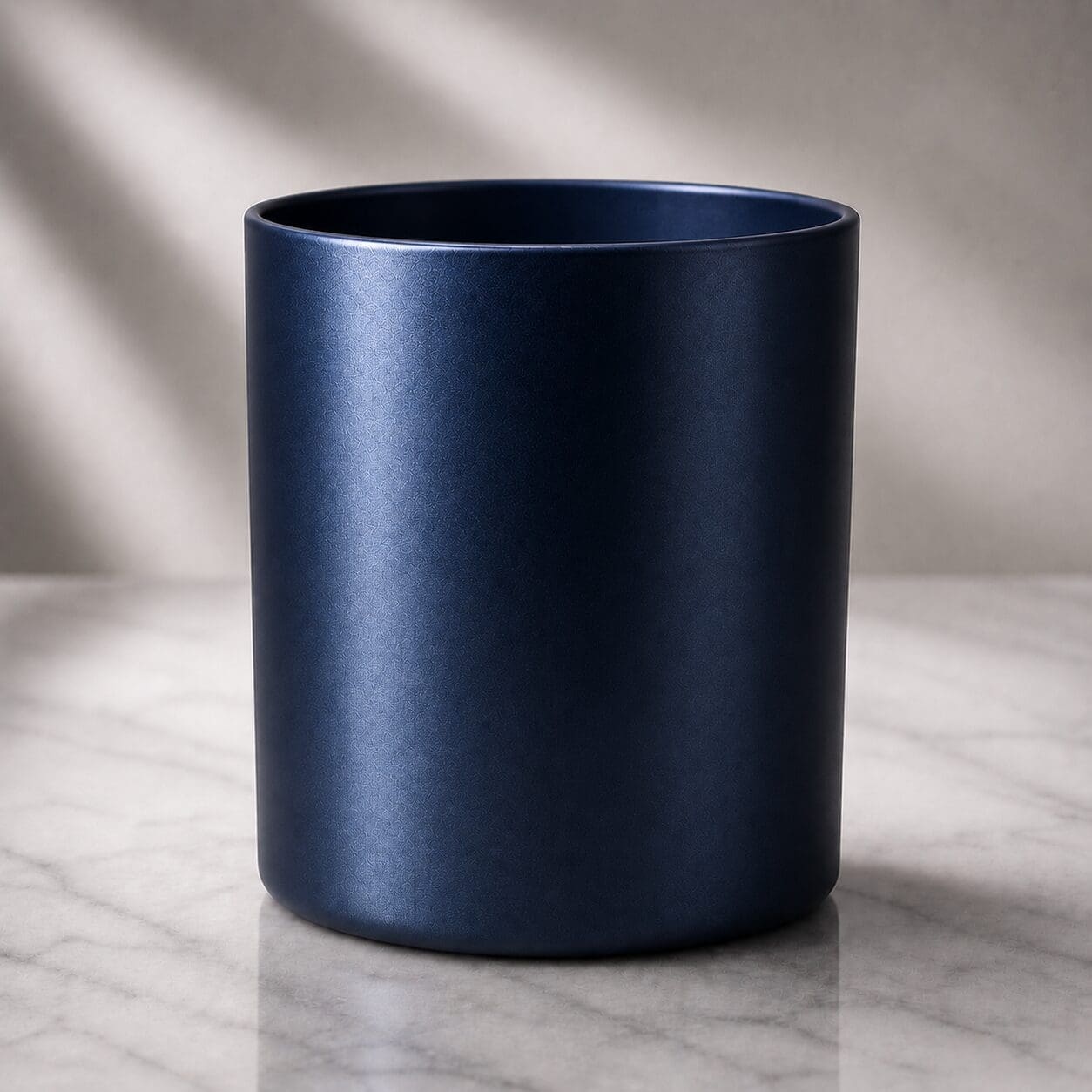 Navy blue matte cylindrical vessel on marble surface with soft lighting, suitable for candle filling, perfume bottles, or custom drinkware decorating projects