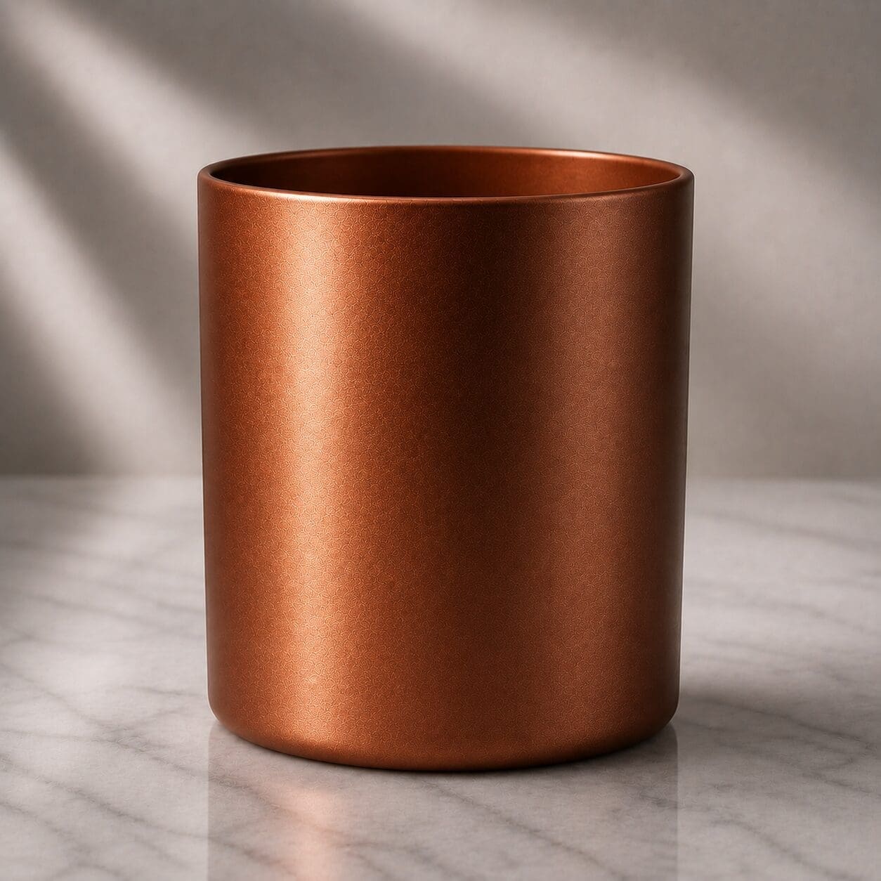 Copper metallic cylindrical vessel with satin finish on marble surface under natural lighting