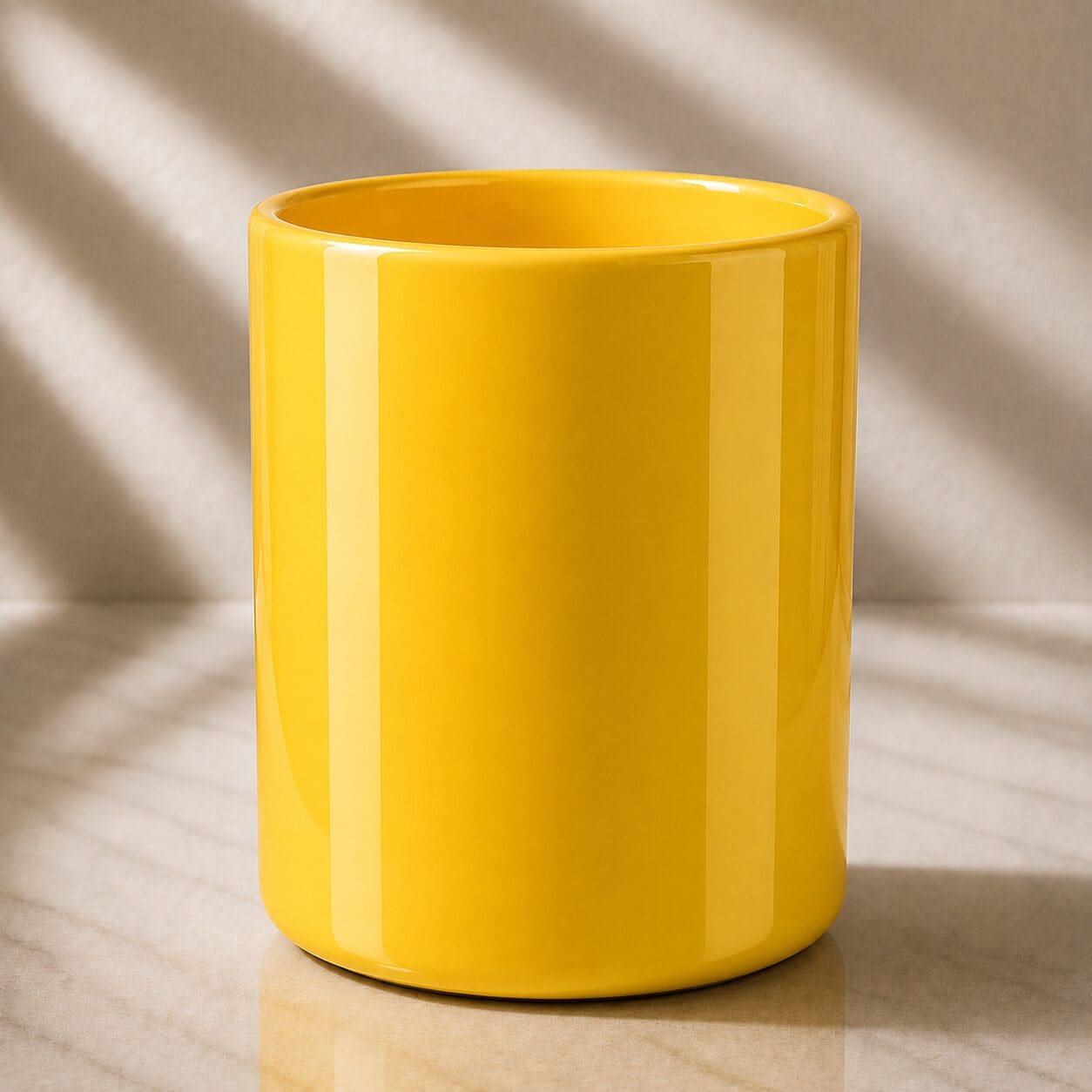 Bright yellow ceramic mug with glossy finish, displayed on marble surface with natural sunlight casting shadows in background