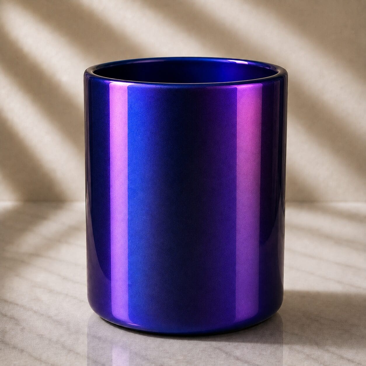 Iridescent blue and purple metallic cylindrical glass container on marble surface with soft lighting