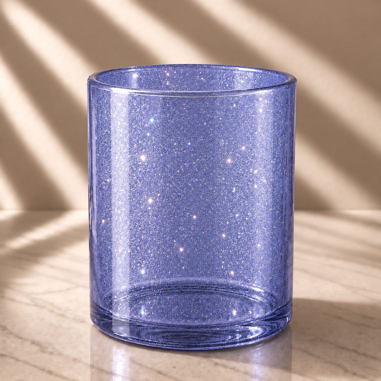 Blue glitter-coated cylindrical glass jar with sparkly spray coating and reflective shimmer, displayed on wooden surface with natural lighting