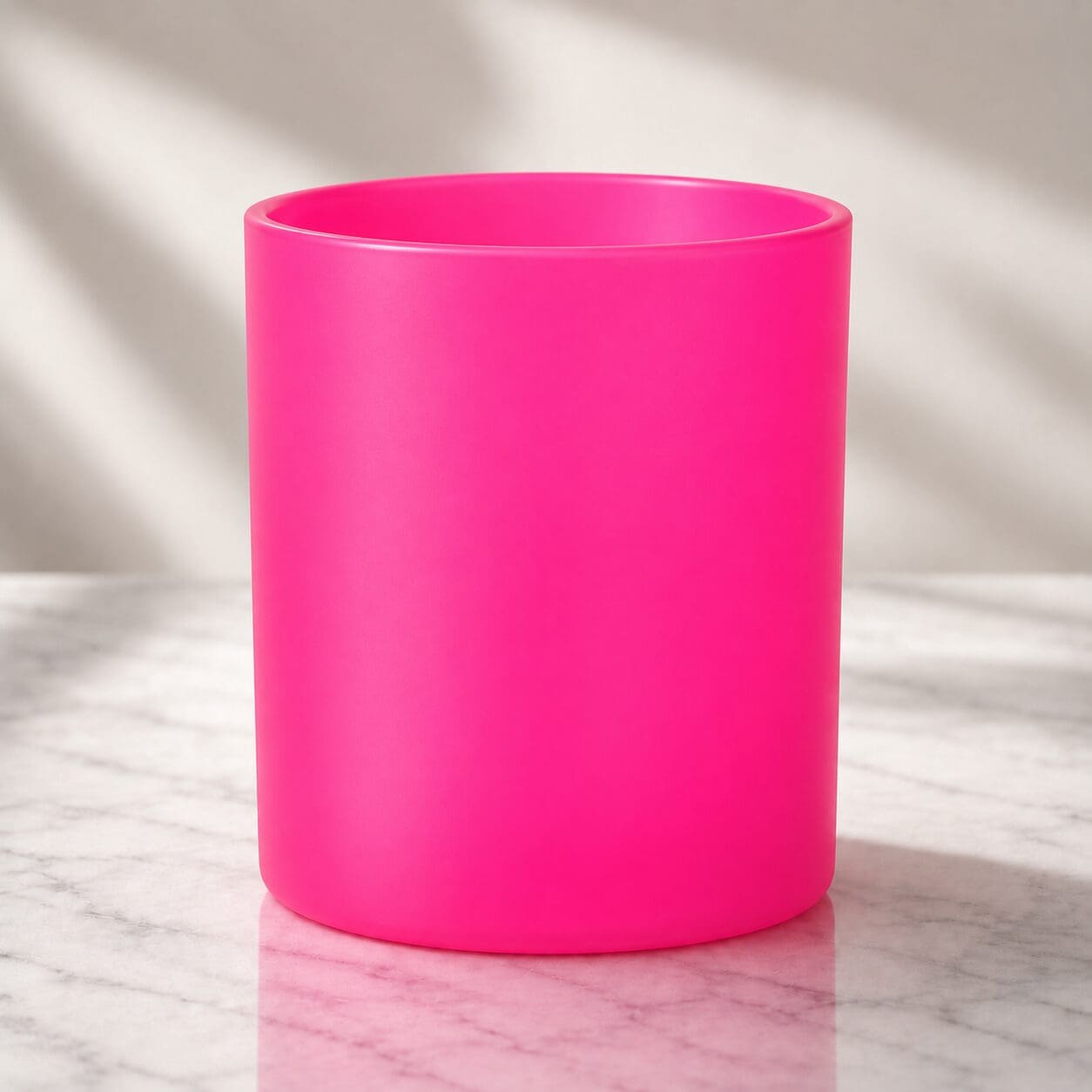 Bright pink cylindrical mug on marble surface with natural lighting, suitable for custom glass decorating and spray coating services