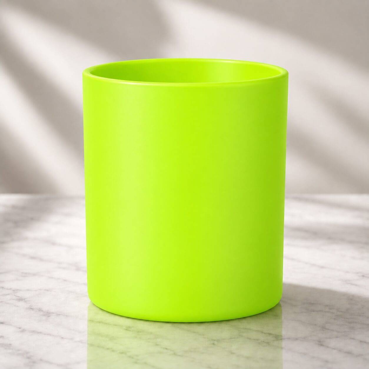 Bright neon green cylindrical mug displayed on marble surface with natural window lighting, showcasing smooth spray coating and vibrant color finish