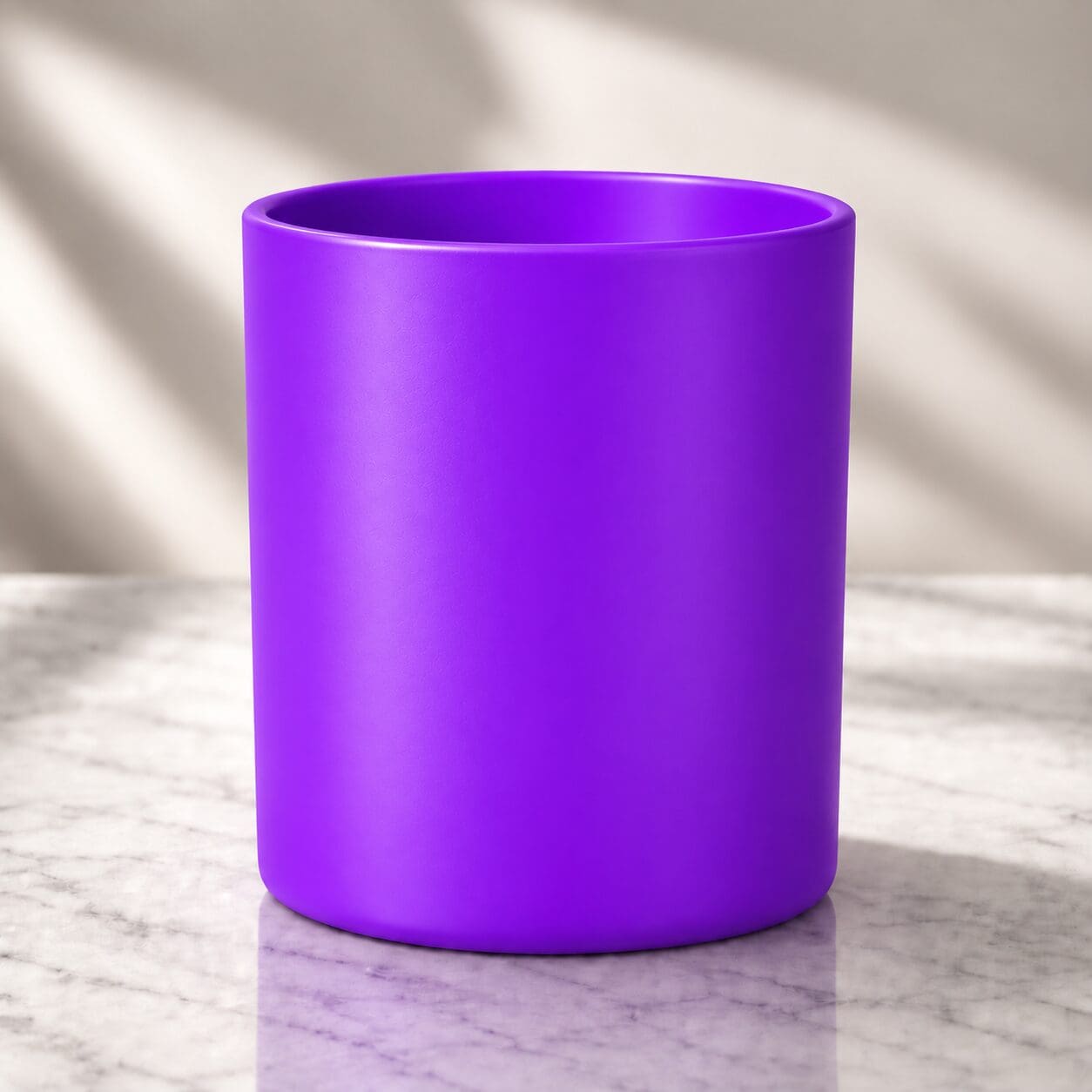 Bright purple cylindrical glass jar with smooth finish displayed on marble surface with natural light casting shadows