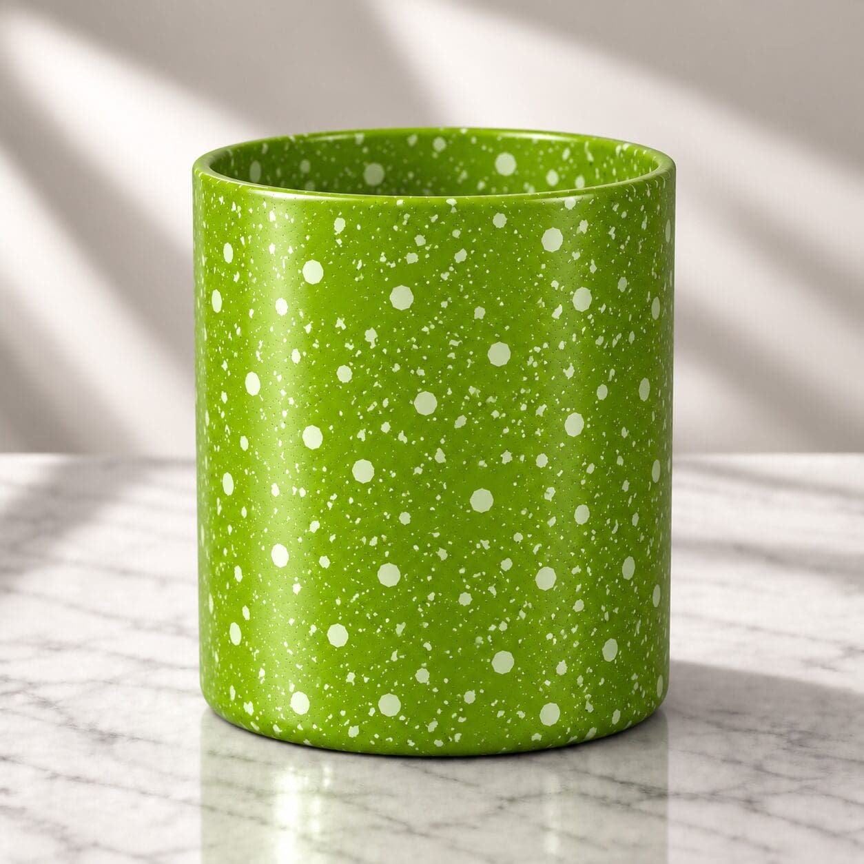 Bright green cylindrical candle jar with white speckled spray coating and polka dot pattern, displayed on marble surface with natural lighting