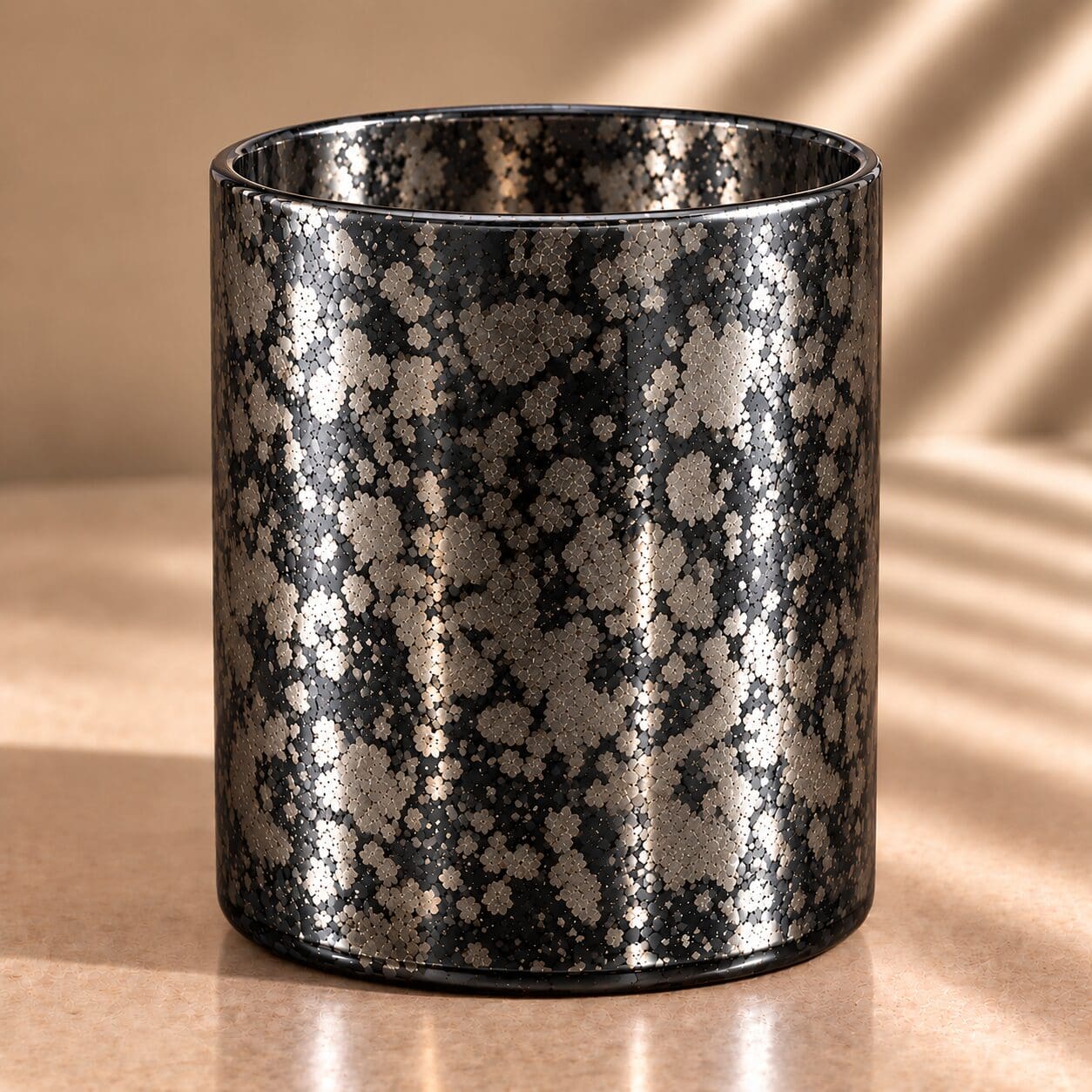 Black cylindrical glass jar with silver and gold speckled spray coating creating a scattered dot pattern throughout