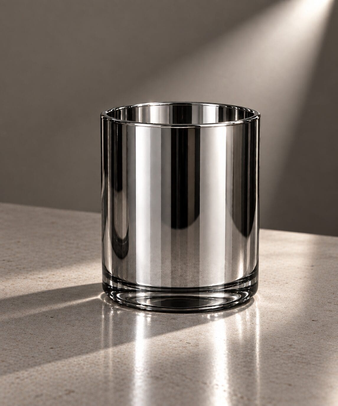 Empty cylindrical glass jar with reflective surface on concrete table under studio lighting