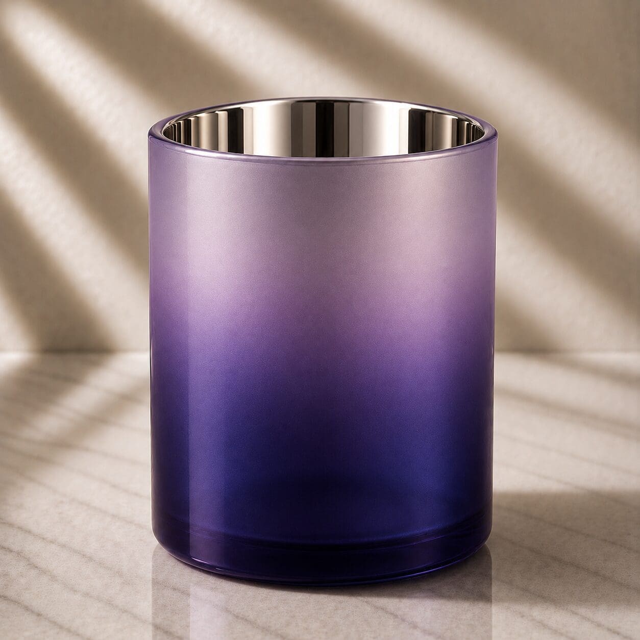 Purple ombre glass cylinder with polished stainless steel rim, displayed on marble surface with natural lighting